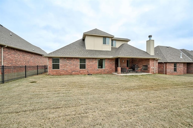 rear view of house featuring a patio area, a yard, a fenced backyard, brick siding, and roof with shingles