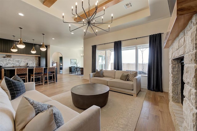 3824 Stone Hill Ln, Edmond, OK 73034 - living area with arched walkways, light wood finished floors, recessed lighting, a fireplace, and a chandelier