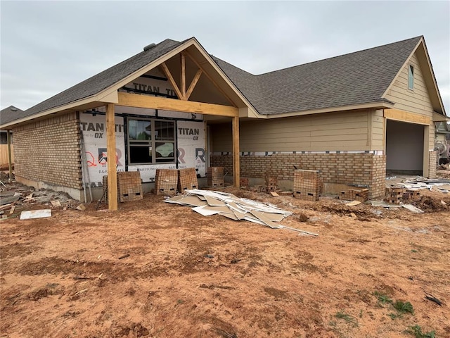 property in mid-construction with brick siding, roof with shingles, and a garage