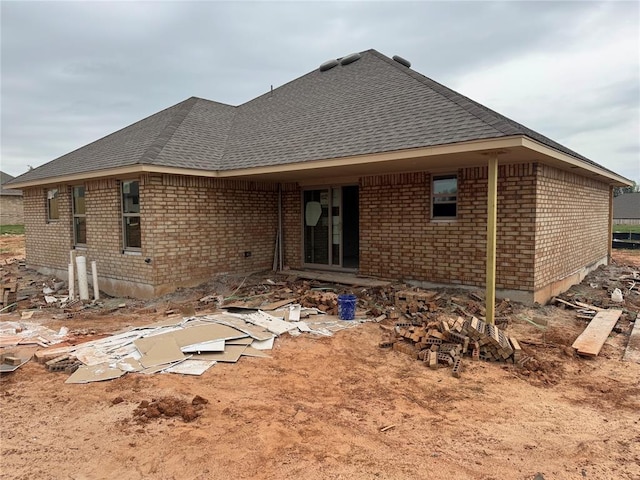 back of property with brick siding and roof with shingles