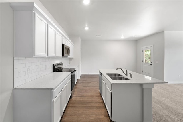 kitchen featuring a kitchen island with sink, white cabinets, tasteful backsplash, a sink, and stainless steel appliances