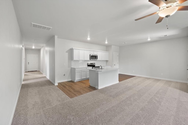 kitchen with appliances with stainless steel finishes, baseboards, carpet flooring, and visible vents