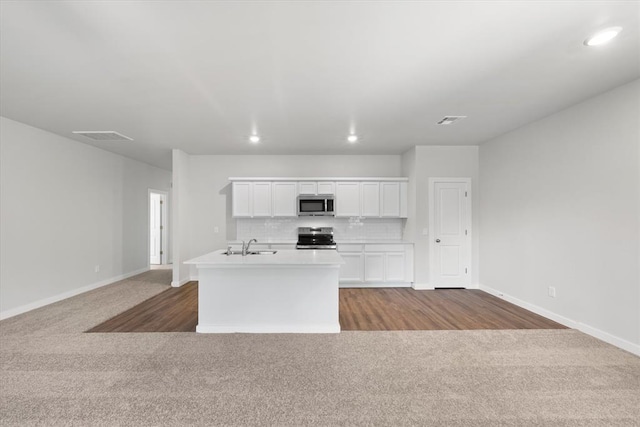 kitchen featuring decorative backsplash, an island with sink, white cabinets, carpet, and stainless steel appliances