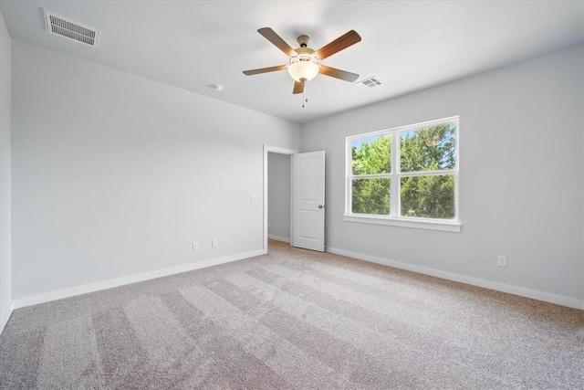 carpeted empty room with baseboards, a ceiling fan, and visible vents