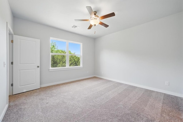 empty room with carpet floors, baseboards, visible vents, and ceiling fan