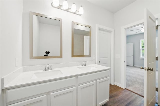 full bath featuring double vanity, a ceiling fan, a sink, and wood finished floors