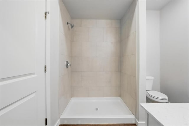 bathroom with vanity, a tile shower, and toilet