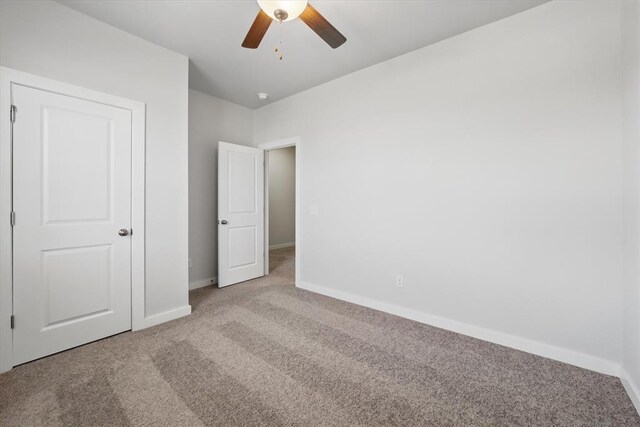 unfurnished bedroom with baseboards, a ceiling fan, and carpet