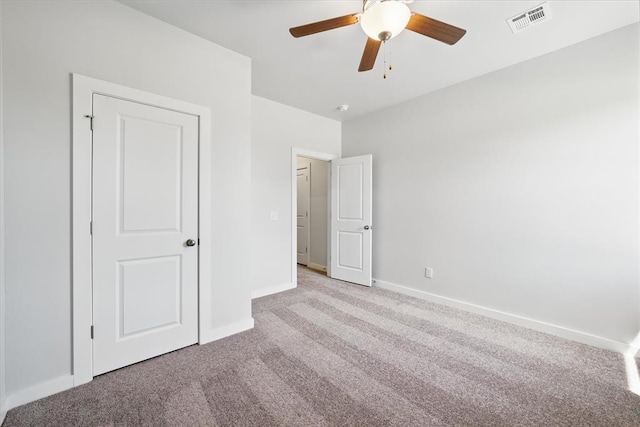 unfurnished bedroom with carpet flooring, a ceiling fan, baseboards, and visible vents