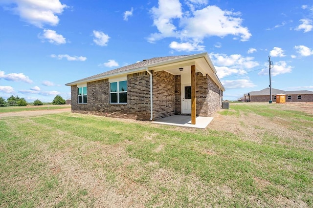 view of front facade featuring brick siding, central AC unit, a patio area, and a front lawn