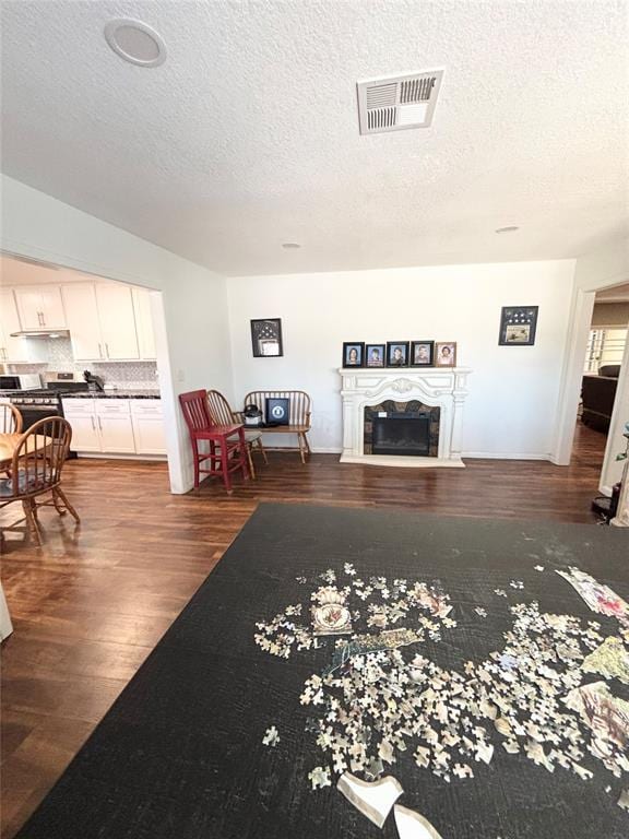 9737 NE State Highway 15, Shattuck, OK 32911 - living area featuring visible vents, wood finished floors, a glass covered fireplace, and a textured ceiling
