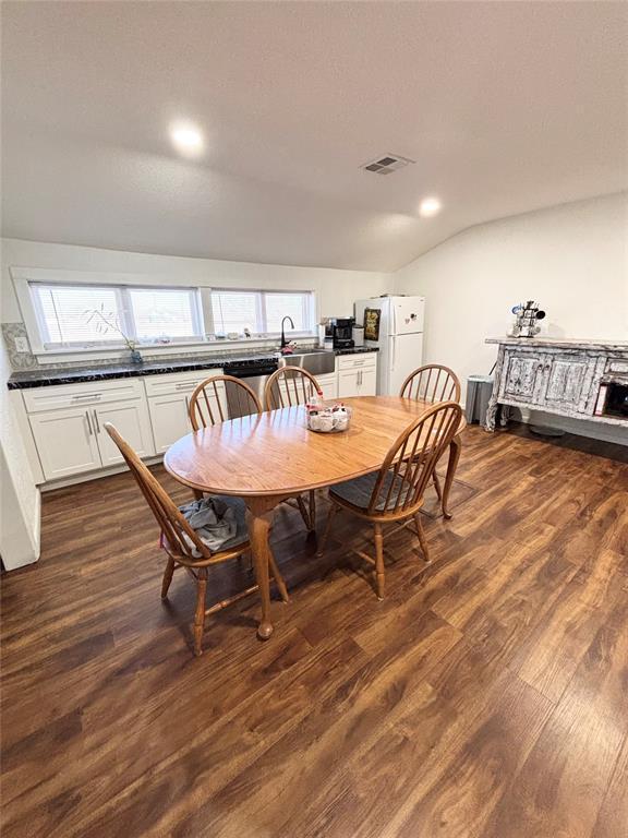 9737 NE State Highway 15, Shattuck, OK 32911 - dining room with dark wood-style floors, visible vents, and vaulted ceiling