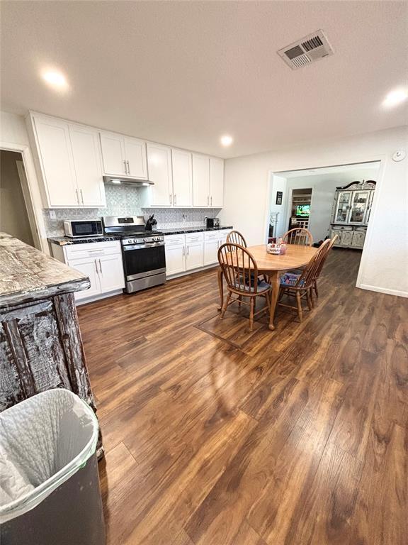 9737 NE State Highway 15, Shattuck, OK 32911 - kitchen featuring stainless steel gas range, white cabinetry, tasteful backsplash, dark wood-style floors, and visible vents