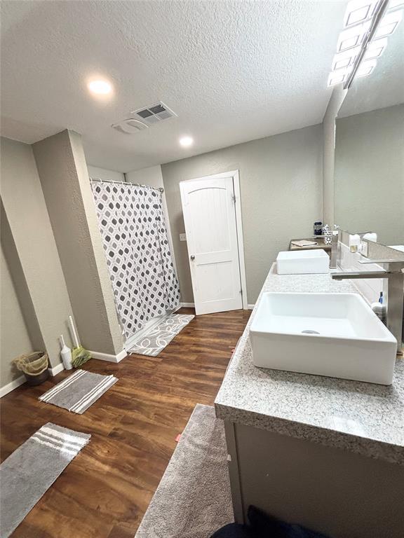 9737 NE State Highway 15, Shattuck, OK 32911 - bathroom with double vanity, curtained shower, wood finished floors, and a sink