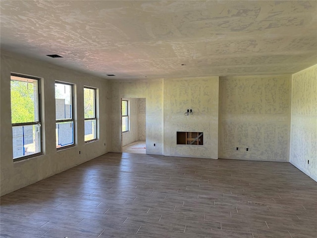 unfurnished living room featuring visible vents, wood finished floors, and a premium fireplace