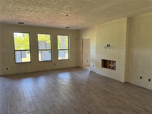 unfurnished living room with visible vents, wood finished floors, and a fireplace