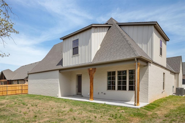 rear view of property featuring fence, roof with shingles, board and batten siding, a patio, and brick siding