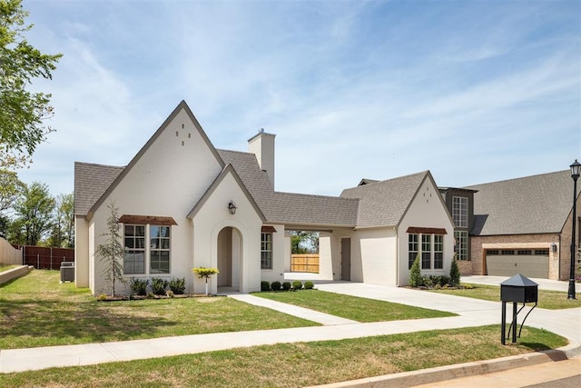 view of front of property with cooling unit, driveway, fence, a garage, and a front yard