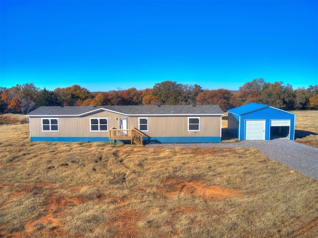 view of front of home featuring an outdoor structure, a detached garage, driveway, and a front lawn