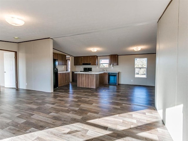 kitchen with dark wood-style flooring, light countertops, a kitchen island, open floor plan, and black appliances