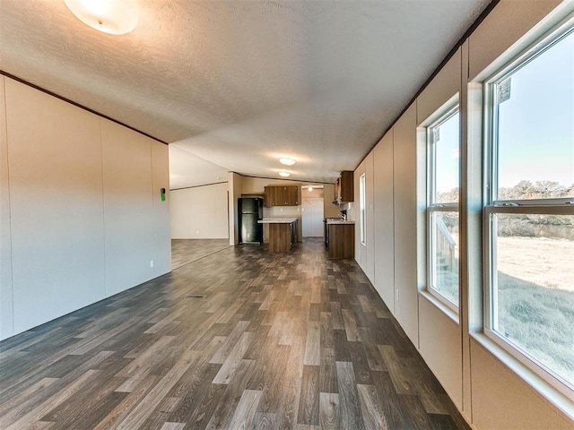 unfurnished living room with dark wood-style floors, vaulted ceiling, and a textured ceiling