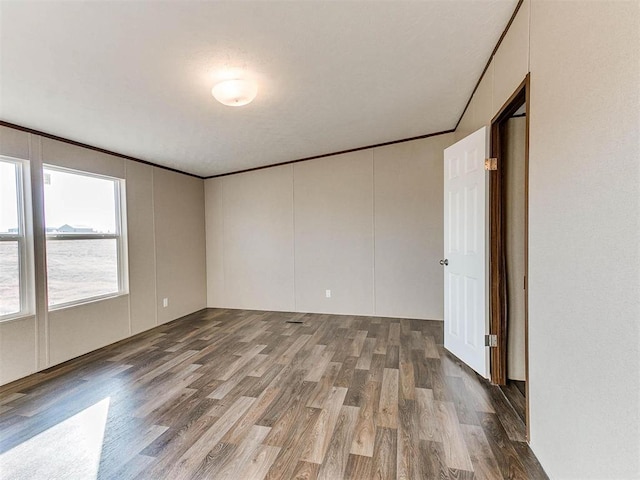 unfurnished room featuring crown molding, wood finished floors, and a decorative wall