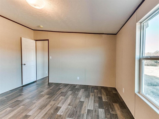 empty room featuring wood finished floors, ornamental molding, and a healthy amount of sunlight
