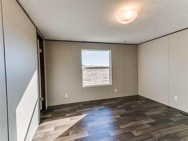 empty room featuring visible vents, wood finished floors, and a textured ceiling