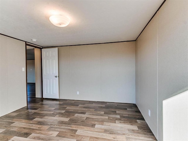 empty room with wood finished floors, a decorative wall, and a textured ceiling