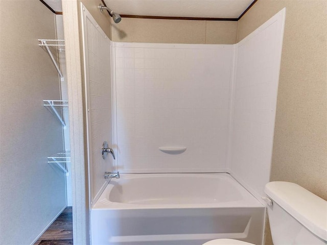 bathroom featuring toilet,  shower combination, and wood finished floors