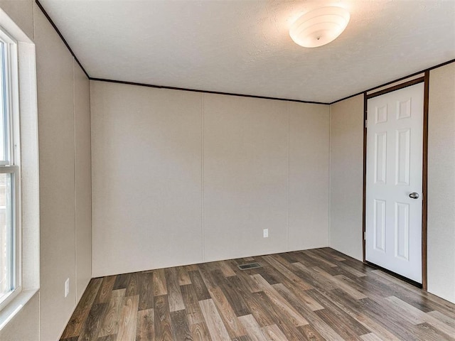 unfurnished bedroom featuring a textured ceiling, ornamental molding, and wood finished floors
