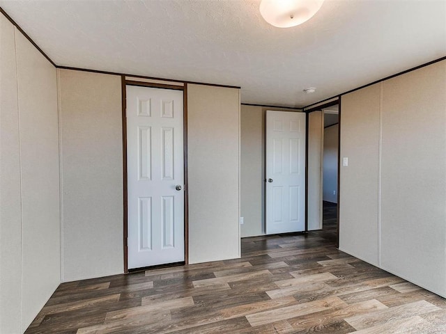 unfurnished bedroom featuring a textured ceiling, crown molding, and wood finished floors
