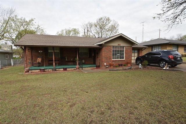 view of front facade featuring brick siding, a front lawn, fence, and covered porch
