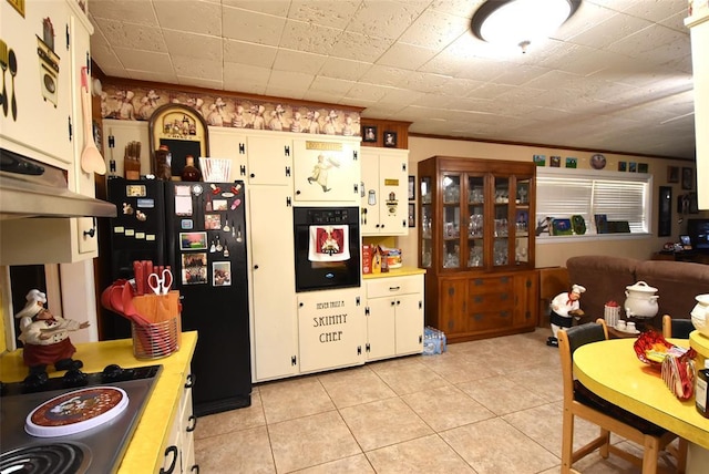 kitchen featuring ornamental molding, light tile patterned floors, white cabinetry, under cabinet range hood, and black appliances
