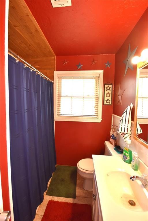 bathroom featuring tile patterned flooring, curtained shower, vanity, and toilet