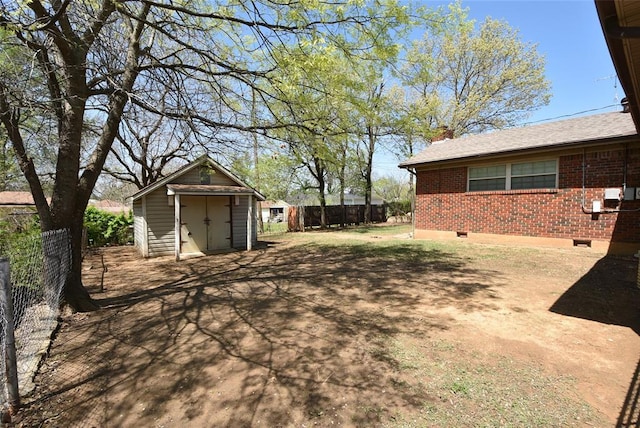 view of yard with a shed, fence, and an outbuilding