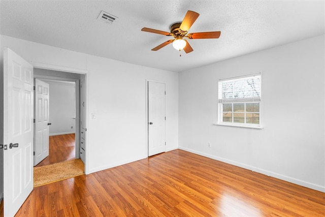 120 E 6th St, Stratford, OK 74872 - unfurnished bedroom with baseboards, visible vents, wood finished floors, and a textured ceiling