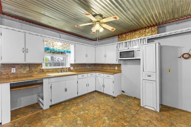 120 E 6th St, Stratford, OK 74872 - kitchen with a sink, backsplash, a ceiling fan, white cabinets, and white microwave