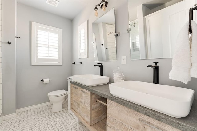 1412 NW 34th St, Oklahoma City, OK 73118 - bathroom with tiled shower, vanity, visible vents, toilet, and baseboards