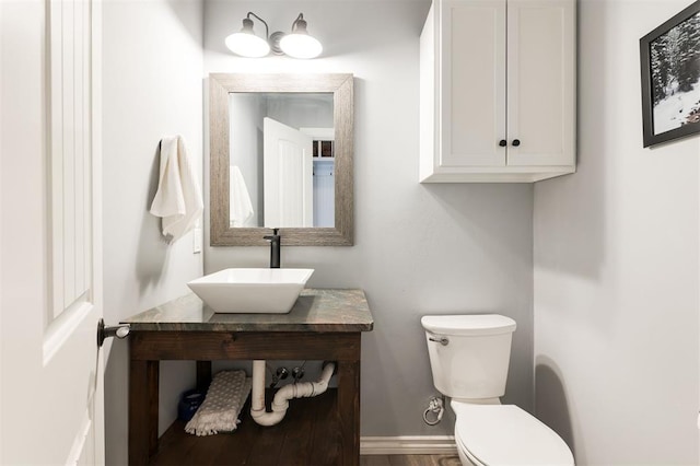 1412 NW 34th St, Oklahoma City, OK 73118 - half bathroom featuring a sink, toilet, wood finished floors, and baseboards