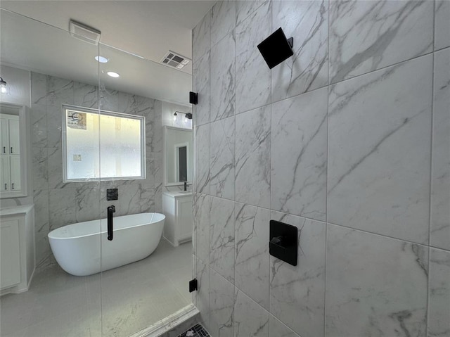 7120 NW 155th St, Edmond, OK 73013 - bathroom with visible vents, a freestanding tub, vanity, and tile walls