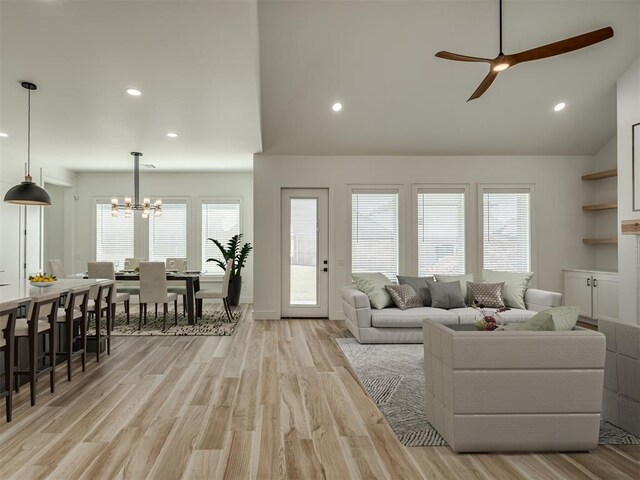 living room featuring recessed lighting, light wood-style flooring, ceiling fan with notable chandelier, and vaulted ceiling