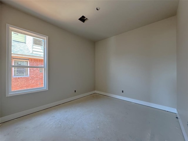 unfurnished room with baseboards and unfinished concrete flooring