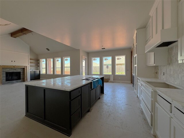 kitchen with dark cabinets, white cabinets, a kitchen island, and a fireplace