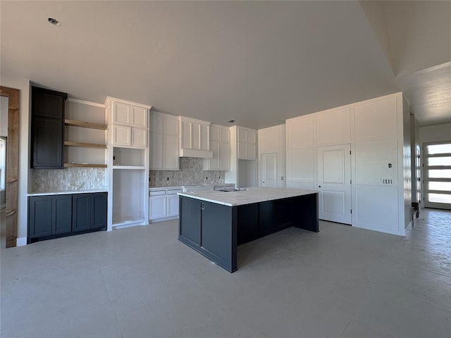 kitchen with white cabinets, light countertops, a center island, decorative backsplash, and under cabinet range hood