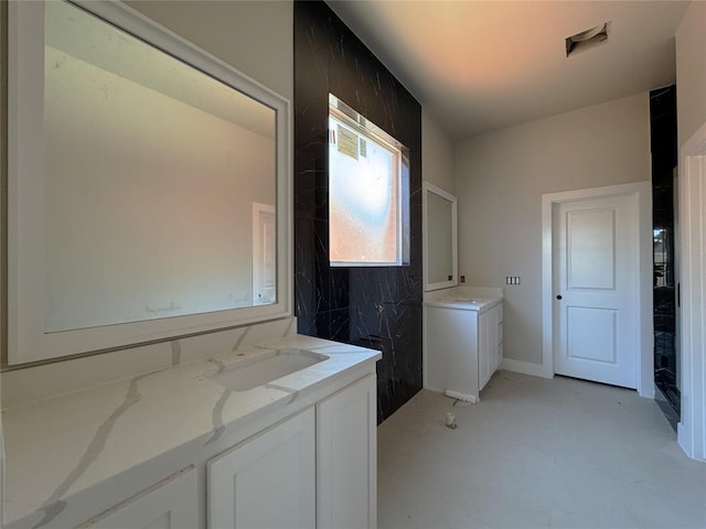 bathroom featuring a sink, concrete floors, and two vanities