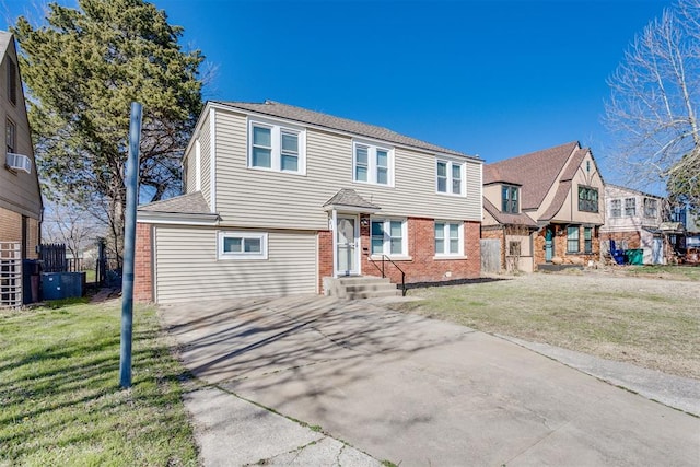 view of front of property featuring brick siding, a front yard, concrete driveway, and fence