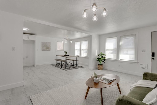 living area with baseboards, marble finish floor, a textured ceiling, and a notable chandelier