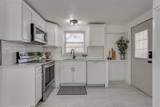 kitchen featuring light countertops, white cabinets, a sink, and appliances with stainless steel finishes