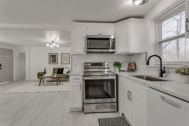 kitchen featuring white cabinetry, tasteful backsplash, a sink, light stone counters, and appliances with stainless steel finishes